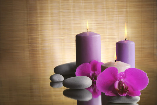 Spa composition with candles, pebbles and flowers on the table, close up
