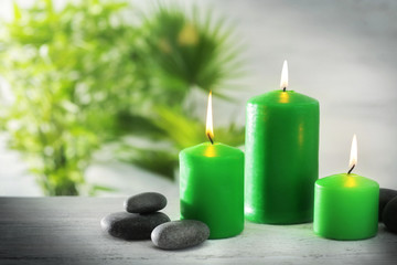 Fototapeta na wymiar Green candles with spa stones and bamboo on table