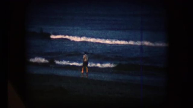 View of a man walking along the beach in the mid 1960's