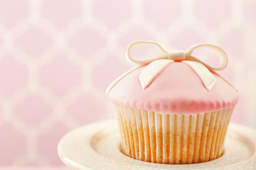 Tasty cupcake with bow on bright background