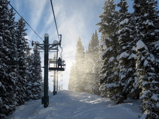 Silhouette of skier on a chair lift against blowing snow