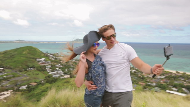 Happy couple taking selfie self-portrait on hike smiling at camera outdoors at Pillbox Hike, Oahu, Hawaii.