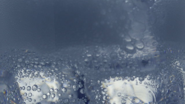 Pouring soda water with ice and bubbles in the glass. Сlose-up 4K UHD 2160p footage.
