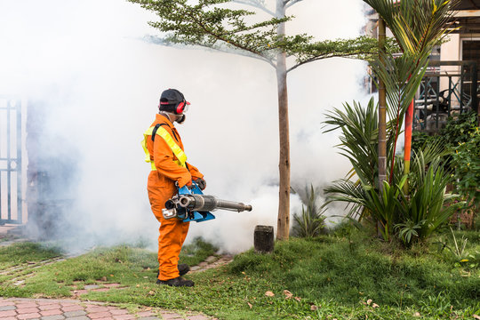 Worker fogging residential area with insecticides to kill aedes mosquito breeding cycle