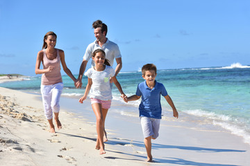 Family of four running on a sandy caribbean beach