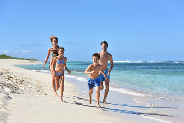 Family runnning on a sandy beach in Caribbean island