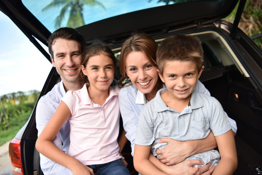Family sitting in car trunk, ready for vacation