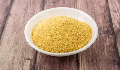 Dried bakers yeast in white bowl over wooden background