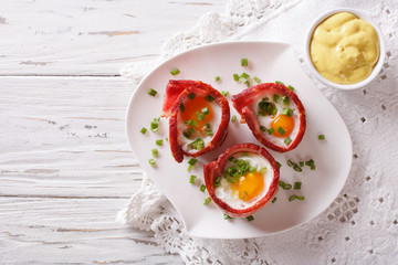 Fried eggs wrapped in crispy bacon and sauce. Horizontal top view
