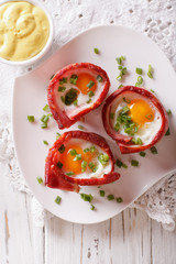 Fried eggs wrapped in bacon close-up and sauce. vertical top view
