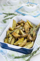 Slices of baked potatoes with rosemary in a ceramic form