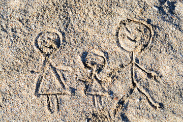 Happy family drawing on beach sand in the summer