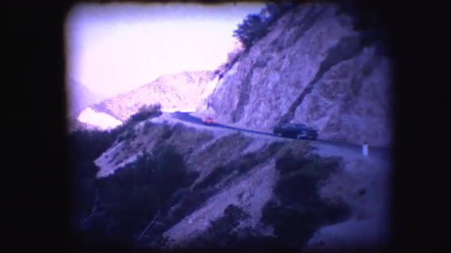 Vintage 8mm footage of cars driving on a mountain pass