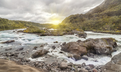 Mountain fast flowing river stream of water in the rocks with cloudy sky