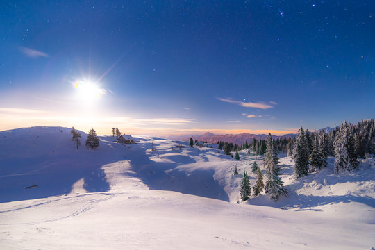 Landschaft im Winter bei Schnee und einer kleinen Almhütte im Hang