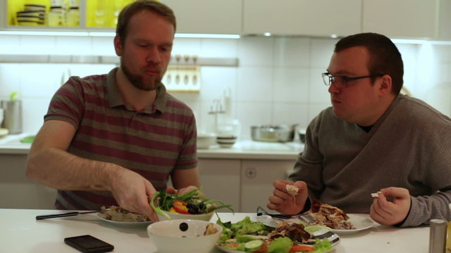 Two man eating chicken and vegetables