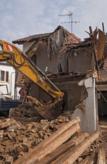 Fototapeta na wymiar A large track hoe excavator tearing down an old house