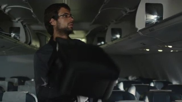 Young man and woman are entering the cabin of an airplane and sitting down.