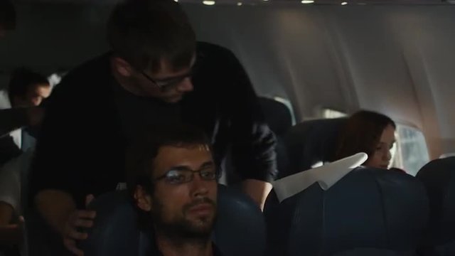 People are entering the cabin of an airplane and sitting down.