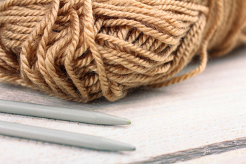 brown yarn for knitting with spokes on white wooden background