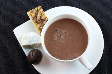 Eine Tasse heiße Schokolade mit Keksen und Pralinen