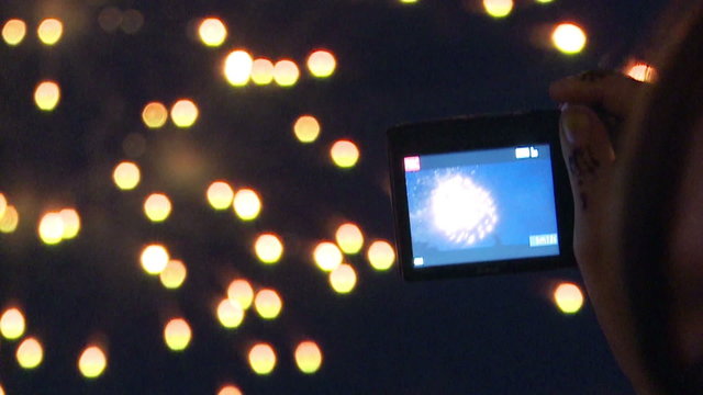 Young girl filming fireworks with her camera,editorial