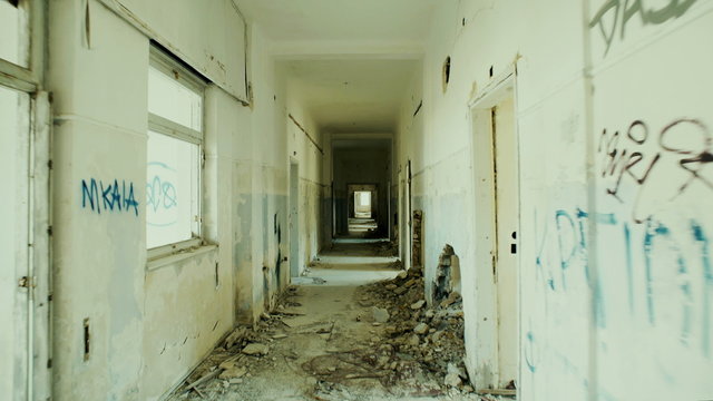 4K UHD Walking through an abandoned long corridor.Gimbal/steadycam stabilized pov shot of someone walking inside a very long corridor of a destroyed sanitorium.Destruction and abandonment