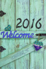 Welcome sign with year 2016 and hearts hanging on rustic mint green door