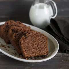 Simple delicious chocolate cake on an oval plate on a dark wooden table.