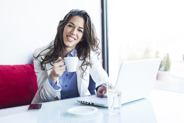 Businesswoman in a coffee shop working on the lap top and having a coffee
