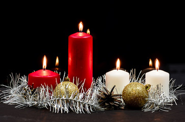 Burning candles on black reflected background with garland