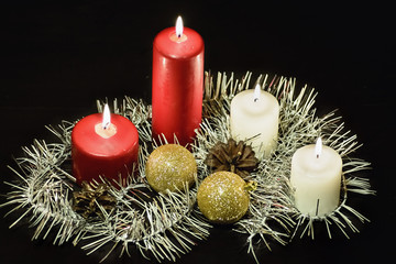Burning candles on black background with garland