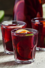 Sangria with fruit in a glass and a jug on old wooden background