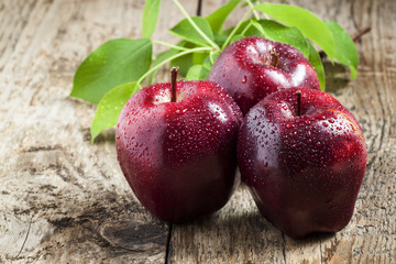 Red and burgundy apple with drops of water on the old wooden bac