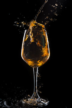 Red wine pouring into  wine glass. Isolated on black background