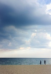 Fototapeta premium Two people walking along sandy ocean beach