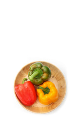 fresh bell peppers in wooden bowl on white background