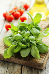 Basil leaves on cutting board on grey wooden background