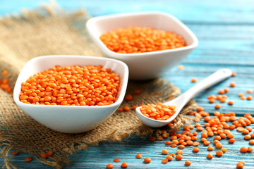 Red lentils in bowl on a blue wooden table