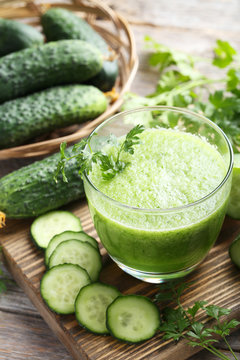Glass of fresh cucumber juice on grey wooden table