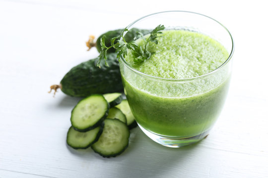 Glass of fresh cucumber juice on white wooden table