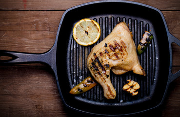 Chiken and vegetables on grill pan on old wooden table or board.