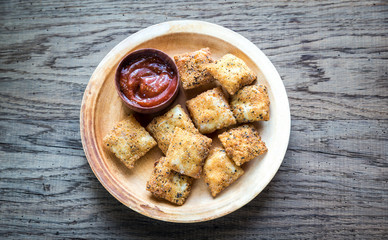Plate with fried ravioli on the wooden board