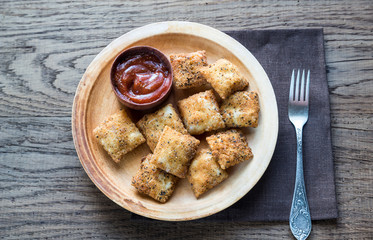 Plate with fried ravioli on the wooden board