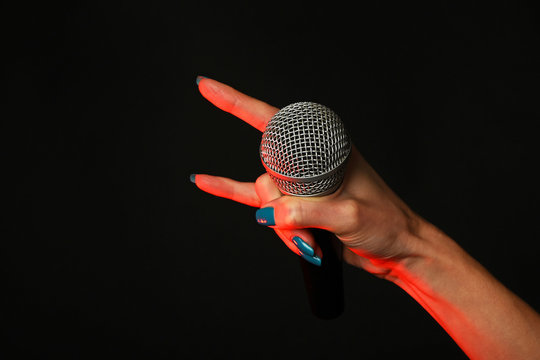 Woman Hand With Microphone And Devil Horns On Black