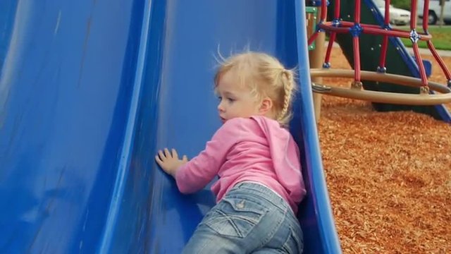 Adorable toddler tries to climb the slide but just can't seem to make it to the top