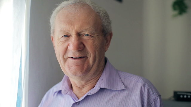 The old man smiles at the camera