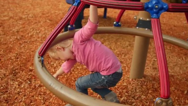 Young girl plays underneath the jungle gym