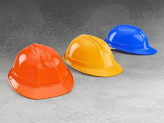 orange, yellow and blue safety helmet on concrete background