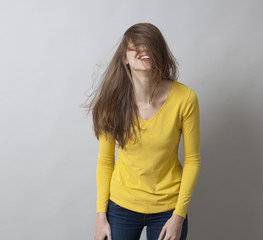 excitement and humor concept - giggling 20s girl messing up her hair for fun,covering her smiling...